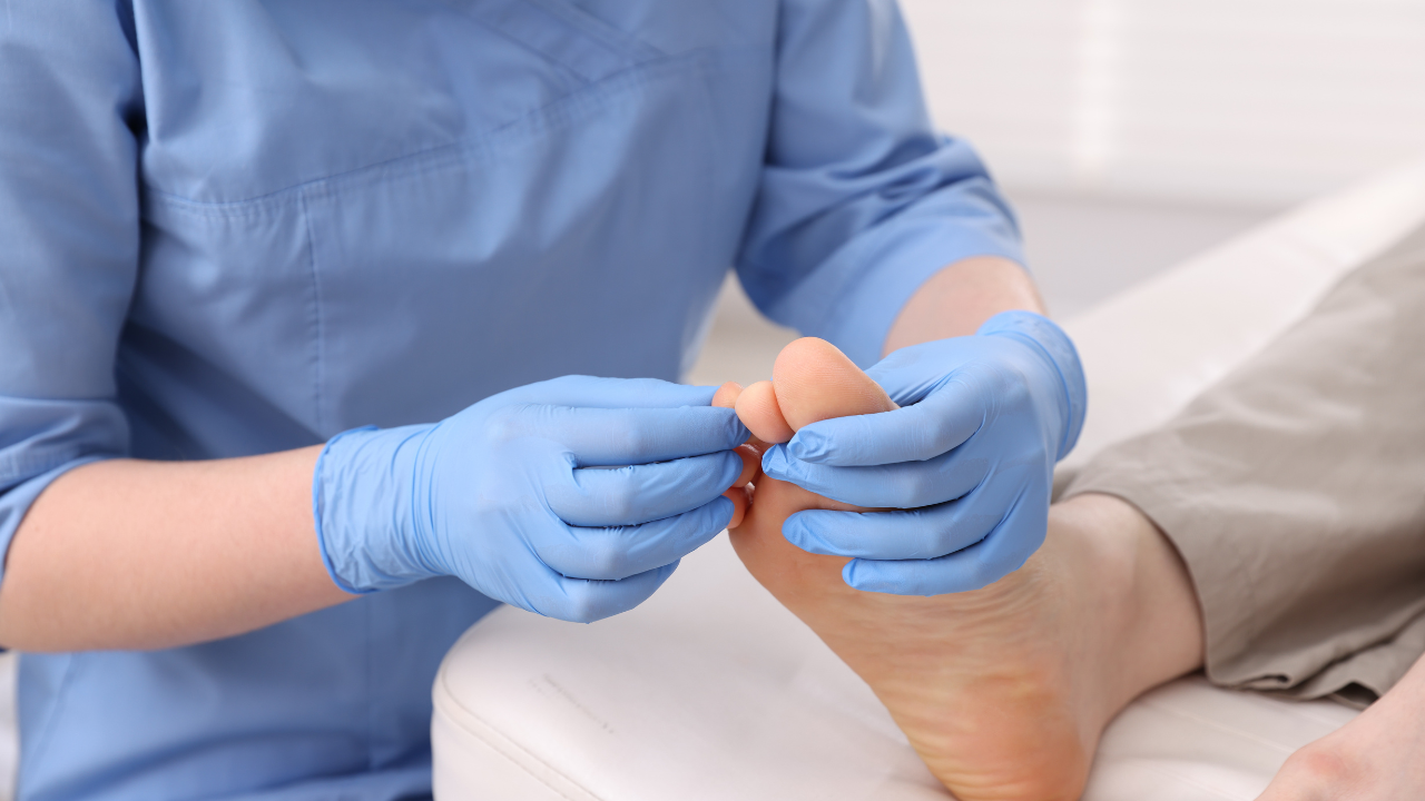 Provider in blue gloves examining a patient's toes